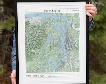 May include: A framed map of Puget Sound, Washington, USA. The map shows the coastline and islands of the Puget Sound region. The map is printed in black and white with green and blue accents. The map is framed in black.