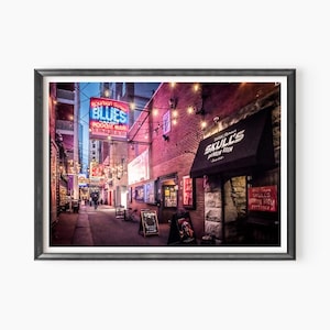 May include: A narrow, brick alleyway at night with neon signs for "Bourbon Street Blues and Boogie Bar" and "Skull's Tavern Room". String lights hang overhead, illuminating the brick walls and the sidewalk.
