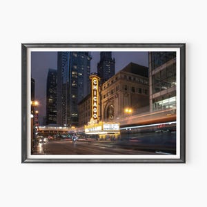 May include: A nighttime view of the Chicago Theater marquee with the word "CHICAGO" lit up in yellow neon. The theater is located on a busy street with tall buildings in the background.