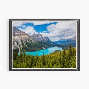 Peut inclure: Vue panoramique d'un lac turquoise niché dans une vallée entourée de montagnes enneigées et d'une forêt luxuriante.