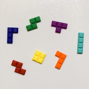 May include: Seven colourful Tetris-shaped blocks in various colours, including green, purple, blue, orange, red, and yellow, on a white background.