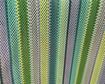 May include: Close-up of a knitted fabric with vertical stripes in shades of green, blue, and gray. The open weave creates a textured effect. The fabric appears to be a lightweight material, suitable for a blanket or throw.