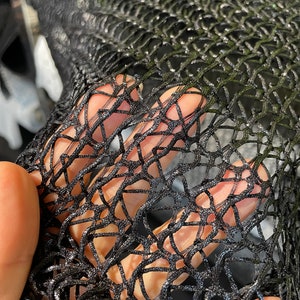 May include: Black mesh fabric with a fine, intricate pattern. The fabric is soft and flexible, and it has a slightly shimmery finish.