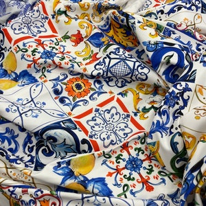 May include: White fabric with a colorful tile pattern. The pattern features blue, red, yellow, and green tiles with floral and geometric designs.