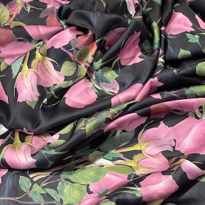 May include: Black fabric with a pink rose print. The fabric is draped and folded, showing the pattern.