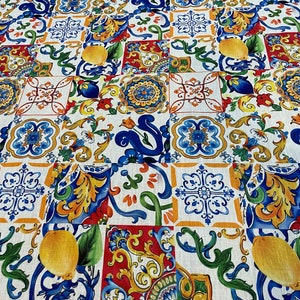 May include: A white fabric with a repeating pattern of colorful Italian-style tiles. The tiles feature blue, yellow, green, red, and white colors and intricate floral designs.