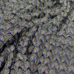 Puede incluir: Primer plano de una tela con un patr&oacute;n texturizado e iridiscente. La tela es de color verde oscuro con toques de azul y dorado. El patr&oacute;n est&aacute; formado por peque&ntilde;as escamas superpuestas.