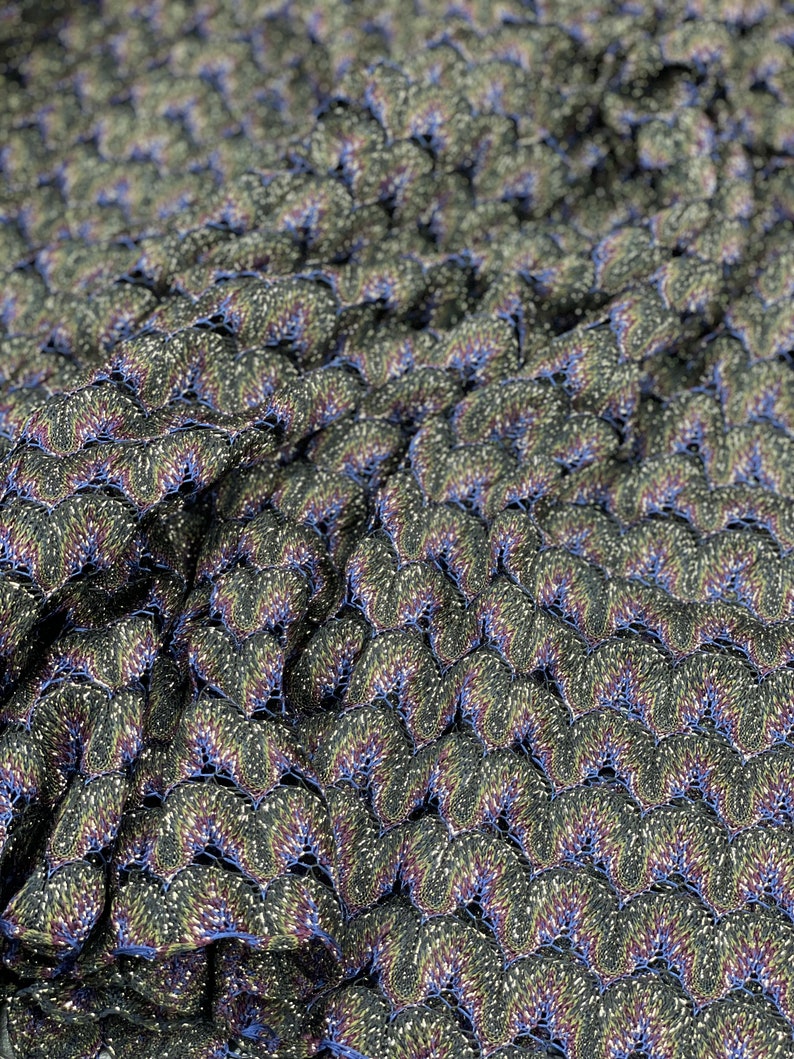 Puede incluir: Primer plano de una tela con un patr&oacute;n texturizado e iridiscente. La tela es de color verde oscuro con toques de azul y dorado. El patr&oacute;n est&aacute; formado por peque&ntilde;as escamas superpuestas.