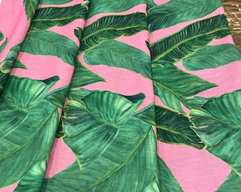 May include: Pink fabric with a green tropical leaf print. The leaves are large and have a realistic appearance.