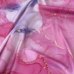 May include: Pink and white fabric with gold accents. The fabric has a marbled pattern with swirls and lines.