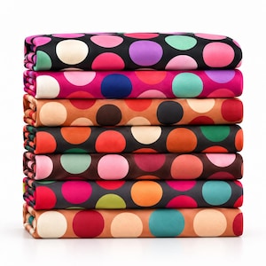 Op de afbeelding: Een stapel van zeven gevouwen stukken stof, elk met een opvallend stippenpatroon. De stoffen vertonen een verscheidenheid aan kleuren, waaronder zwart, roze, oranje, groenblauw, paars en crème, gerangschikt in een verticale kolom op een witte achtergrond.