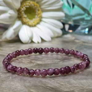 May include: A purple gemstone bracelet with small, round beads. The bracelet is made of natural stones and has a delicate, feminine look.