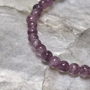 May include: A purple gemstone bracelet with round beads.