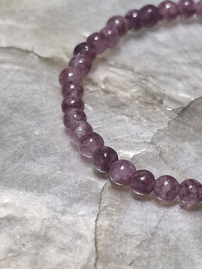 May include: A purple gemstone bracelet with round beads.