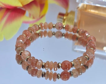 Könnte beinhalten: Ein Armband mit zwei Reihen aus orangefarbenen Sunstone-Perlen und goldenen Zwischenstücken.