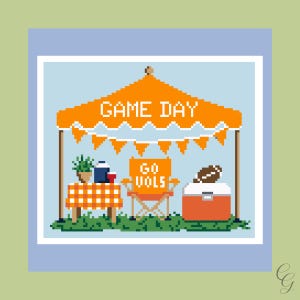 May include: A pixel art illustration of a tailgate scene under an orange canopy with the text GAME DAY. It features a table with an orange checkered cloth, a folding chair with the text GO VOLS, a cooler, and a football on a light blue background.