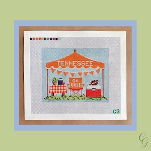 May include: A needlepoint canvas featuring a tailgate scene with an orange tent labeled TENNESSEE, orange bunting, a red and white checkered table, an orange chair with GO VOLS text, a red cooler with a football, and the initials CG in green.