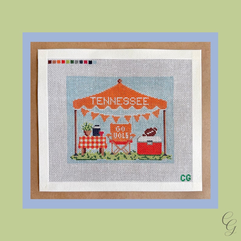 May include: A needlepoint canvas featuring a tailgate scene with an orange tent labeled TENNESSEE, orange bunting, a red and white checkered table, an orange chair with GO VOLS text, a red cooler with a football, and the initials CG in green.
