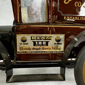 Puede incluir: Una jarra de cer&aacute;mica marr&oacute;n con forma de cami&oacute;n antiguo, con el texto "BEAM" y "Kentucky Straight Bourbon Whiskey". La jarra tiene una ventana plateada y letras doradas. Se lee "4/5 Quart" y "100 Months Old".