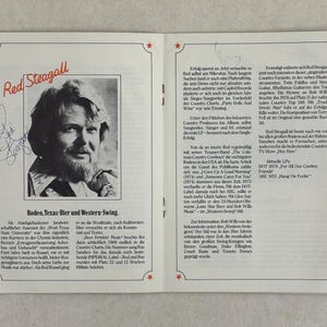 May include: An open book featuring a black and white portrait of Red Steagall, with his signature. The text includes "Rodeo, Texas-Bier und Western Swing" and details about his career and music.
