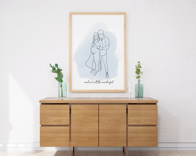 May include: A framed line drawing of a couple embracing, with a blue watercolor background. The text "and we will be wonderful" is below the drawing.