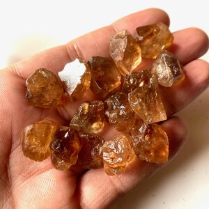 Puede incluir: Un pu&ntilde;ado de cristales de citrino en bruto y sin cortar. Los cristales son de un color &aacute;mbar c&aacute;lido, con una textura natural rugosa. Las piedras preciosas var&iacute;an en tama&ntilde;o y forma, algunas parecen m&aacute;s transl&uacute;cidas. Citrino natural.