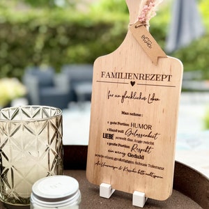Könnte beinhalten: Holzschneidebrett mit einem Herzen und dem Text "Familienrezept für ein glückliches Leben". Das Brett listet auch Zutaten für ein glückliches Leben auf, darunter Humor, Gelassenheit, Liebe, Respekt, Geduld und Toleranz.