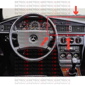 以下が含まれることがあります： 黒いダッシュボード、ステアリングホイール、さまざまなコントロールを備えた車のインテリア。ダッシュボードは黒と銀のデザインで、中央に換気口があります。ステアリングホイールは黒革製で、銀色のメルセデス・ベンツのロゴが付いています。