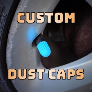 May include: Close-up of a car tyre valve stem with a blue dust cap. The text "CUSTOM DUST CAPS" is displayed in orange on the tyre.