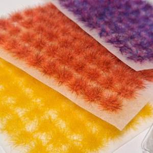 Peut inclure: Trois feuilles d'herbe statique pour modélisme ferroviaire dans différentes couleurs : jaune, orange et violet. L'herbe est disposée en pile, avec la feuille jaune en bas, la feuille orange au milieu et la feuille violette en haut.