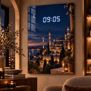 May include: A rectangular wall clock featuring a high-resolution night scene of a mosque with illuminated minarets and domes by a waterfront. The digital display shows the time 09:05 in bright white light against the dark blue evening sky.