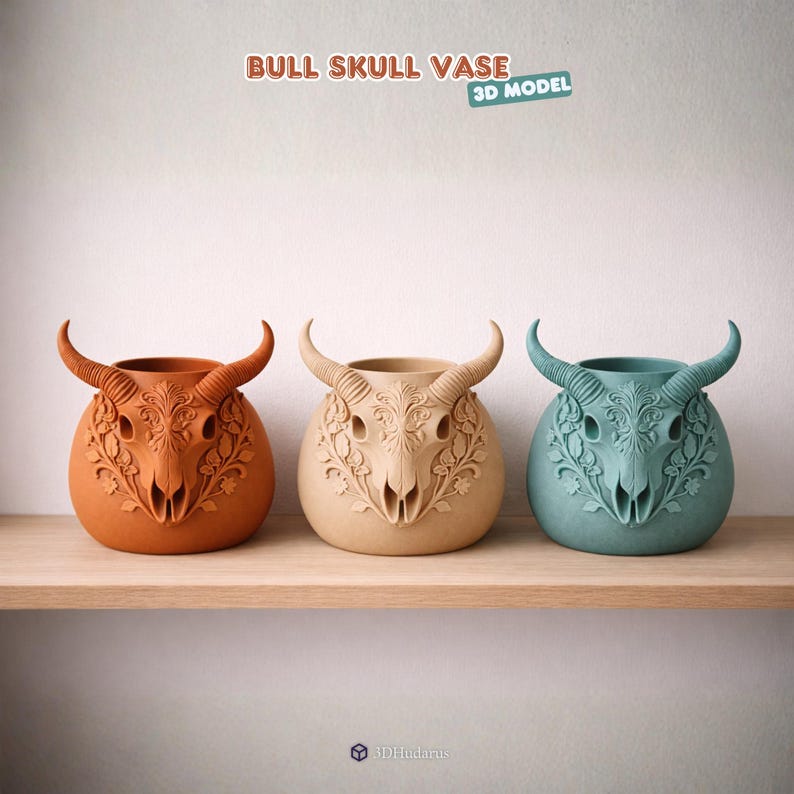 Puede incluir: Tres jarrones con forma de calavera de toro en naranja, beige y turquesa, cada uno con intrincados dise&ntilde;os florales y cuernos curvos. Los jarrones se exhiben en una estanter&iacute;a de madera sobre un fondo blanco. El texto "BULL SKULL VASE 3D MODEL" est&aacute; en la parte superior.
