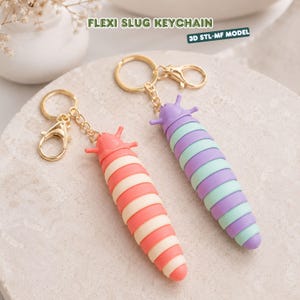 May include: Two flexi slug keychains with gold-tone metal rings and lobster clasps. One slug features alternating coral and cream segments, while the other has alternating purple and mint green segments. Text reads FLEXI SLUG KEYCHAIN 3D STL-MF MODEL.