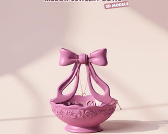 Può includere: Una ciotola portagioie rosa a forma di fiocco, con un fiocco in cima e una base decorativa. La ciotola contiene anelli e una collana con un ciondolo a forma di cuore. Il testo "RIBBON JEWELRY BOWL" e "3D MODELS" sono visibili.