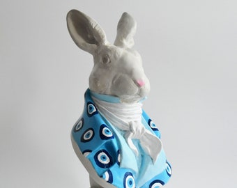 A bust of a white rabbit in a blue frock coat.