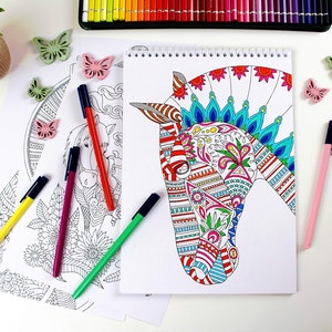 以下が含まれることがあります： 表紙にカラフルな馬の頭を描いた塗り絵。馬は赤、青、緑、黄色の複雑な模様で飾られています。本は空白のページを開いており、塗り絵の準備ができています。