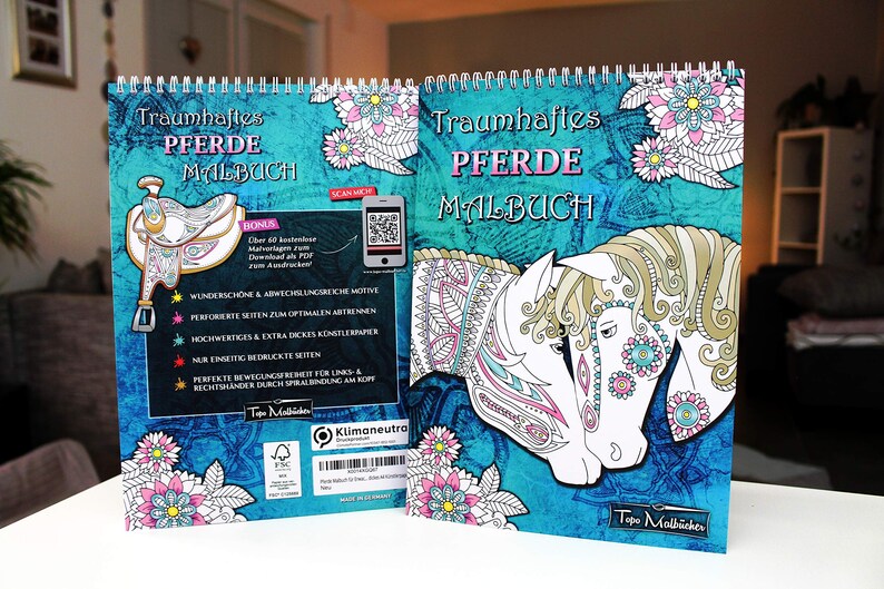 以下が含まれることがあります： 「Traumhaftes Pferde Malbuch」というタイトルの青と白の塗り絵。これは「夢のような馬の塗り絵」という意味です。表紙には、複雑な模様が施された馬のイラストが2つ描かれています。この本は、スパイラル製本で、追加の塗り絵ページのためのボーナスダウンロードコードが付いています。