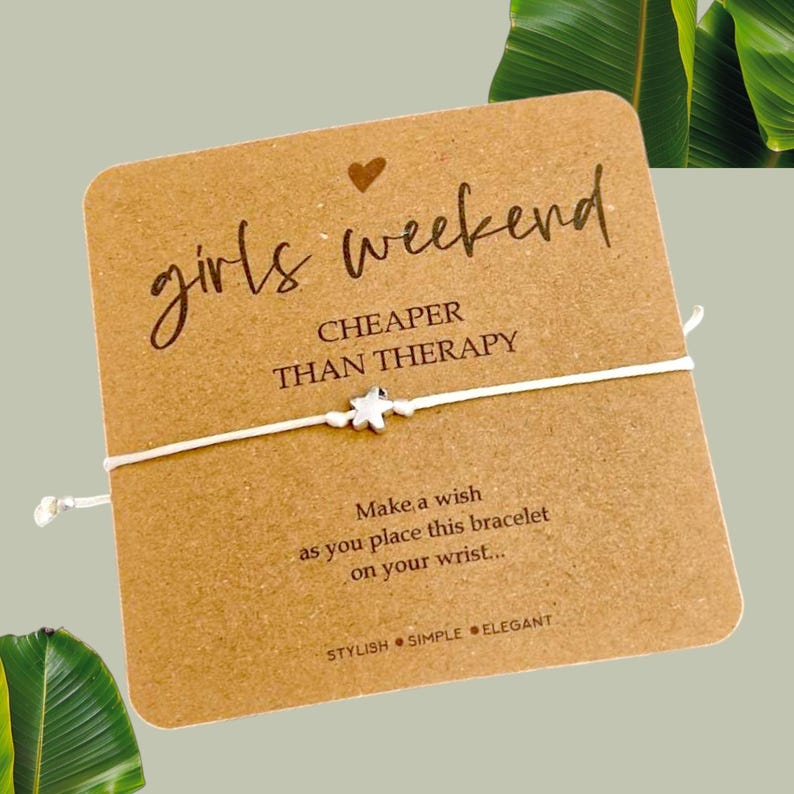 May include: A white string bracelet with a silver star charm. The card reads "girls weekend CHEAPER THAN THERAPY" and "Make a wish as you place this bracelet on your wrist... STYLISH SIMPLE ELEGANT".
