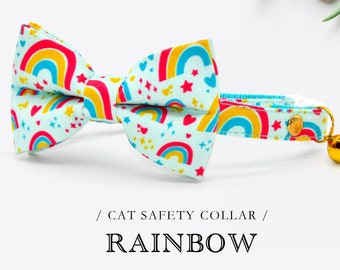 Puede incluir: Un collar de seguridad para gato azul claro con un patrón de arcoíris y una campana. El collar tiene una pajarita con el mismo patrón de arcoíris. El texto "CAT SAFETY COLLAR" y "RAINBOW" está impreso debajo del collar.
