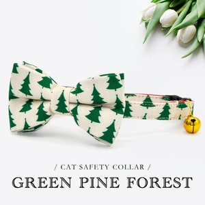 May include: A white cat collar with a green pine tree pattern and a bow tie. The collar has a bell attached to it. / CAT SAFETY COLLAR / GREEN PINE FOREST
