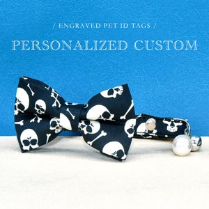 May include: Black and white skull and crossbones patterned cat bow tie with a matching collar and bell.  / ENGRAVED PET ID TAGS / PERSONALIZED CUSTOM