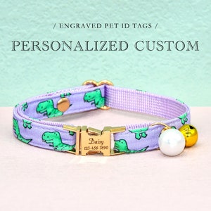 May include: Purple cat collar with a gold buckle and a small gold bell. The collar has a green dinosaur pattern and a gold tag that says "Daisy 123-456-7890".