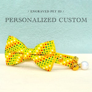 May include: Yellow cat collar with a colorful patterned bow tie and a bell and pearl charm.  Personalized Custom / Engraved Pet ID.