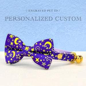 May include: Purple and yellow bow tie with a moon and star pattern. The bow tie is attached to a purple and white collar with a gold bell.
