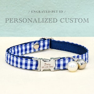 May include: Blue and white gingham patterned pet collar with a silver metal buckle. The collar has a navy blue backing and includes a pearl and silver bell charm. The buckle is engraved with a name and phone number. Text on the image reads "Engraved Pet ID" and "Personalized Custom".