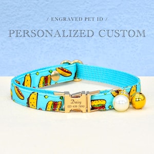May include: A blue pet collar with a hot dog and hamburger print. The collar has a gold buckle with the name "Daisy" and phone number "123-456-7890" engraved on it. The collar also has a pearl charm and a gold bell.