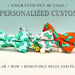 May include: Three pet collars with bow ties featuring a dinosaur print. The collars are in green, white, and orange. Each collar has removable bells and pearls.