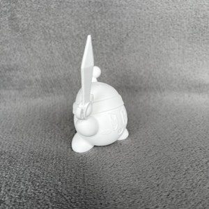 May include: White plastic figurine of a character holding a sword. The character has a round body and a small head with a single eye.