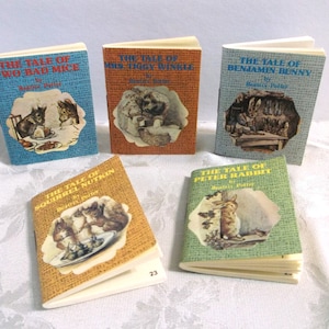 May include: A collection of miniature books with colorful covers. Titles include "The Tale of Two Bad Mice," "Mrs. Tiggy Winkle," "The Tale of Benjamin Bunny," "The Tale of Squirrel Nutkin," and "The Tale of Peter Rabbit." Each book features illustrations.