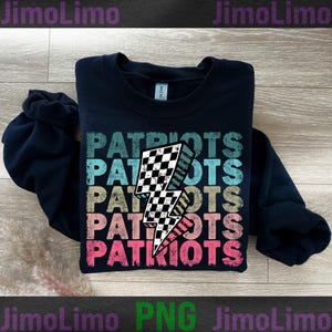 May include: A navy blue sweatshirt with the word "PATRIOTS" stacked vertically in a distressed, multi-colored font. A checkered lightning bolt graphic is centered on the design. The sweatshirt is folded neatly.